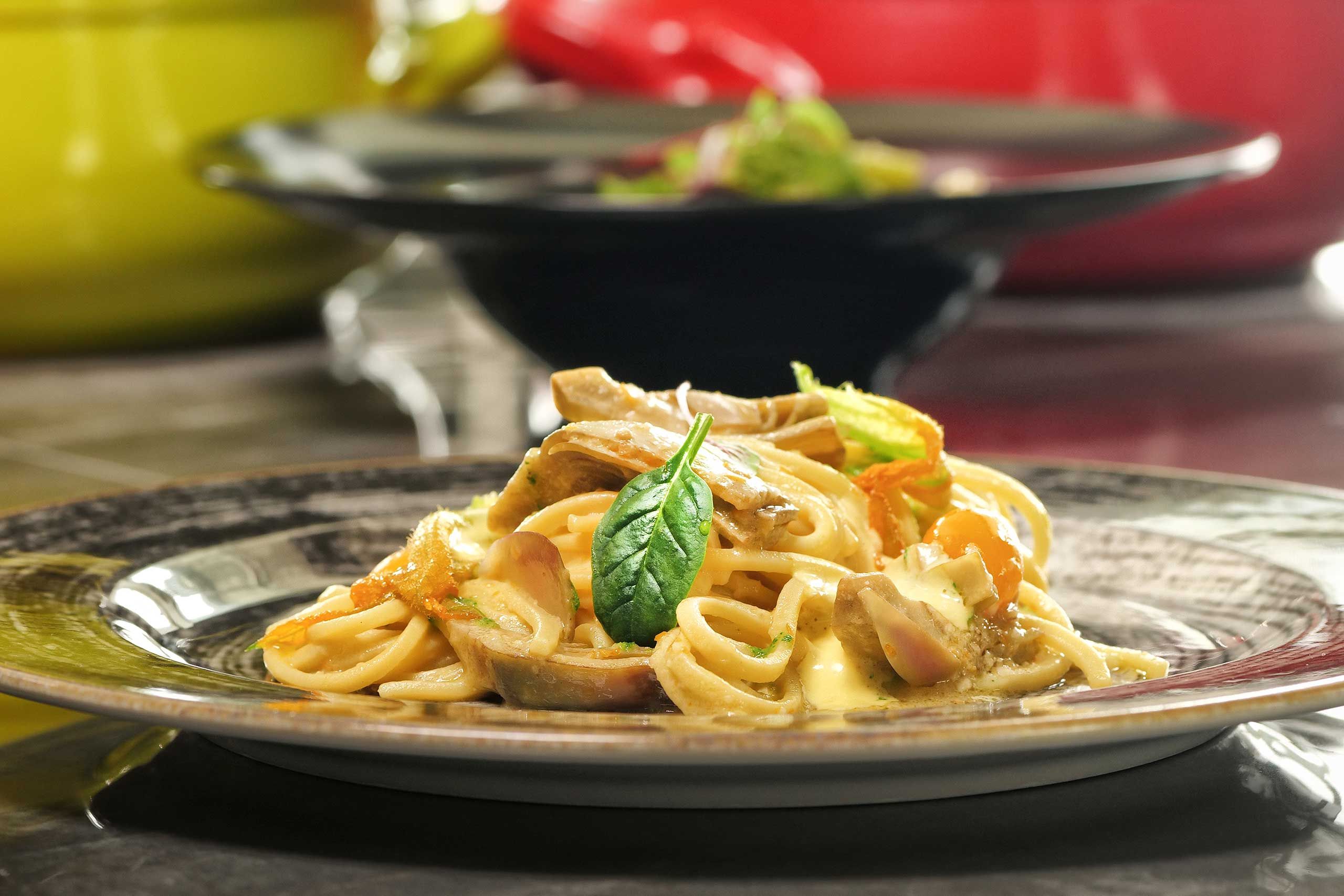 Un plato de pasta con una hoja de albahaca como adorno.