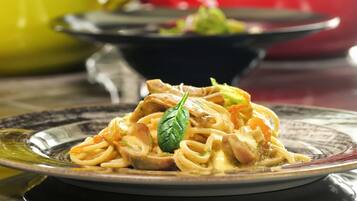Un plato de pasta con una hoja de albahaca como adorno.