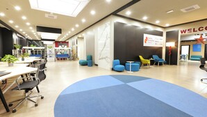 Et moderne kontormiljø med et buet, blåt tæppe, et reception område med et 'WELCOME'-skilt, og et skilt for Salento Biomedical District.