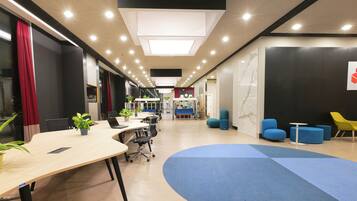 A modern office space with a long table, chairs, and a blue carpeted area.