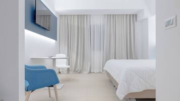 A modern hotel room with a bed, a desk, a chair, and a large window with curtains.