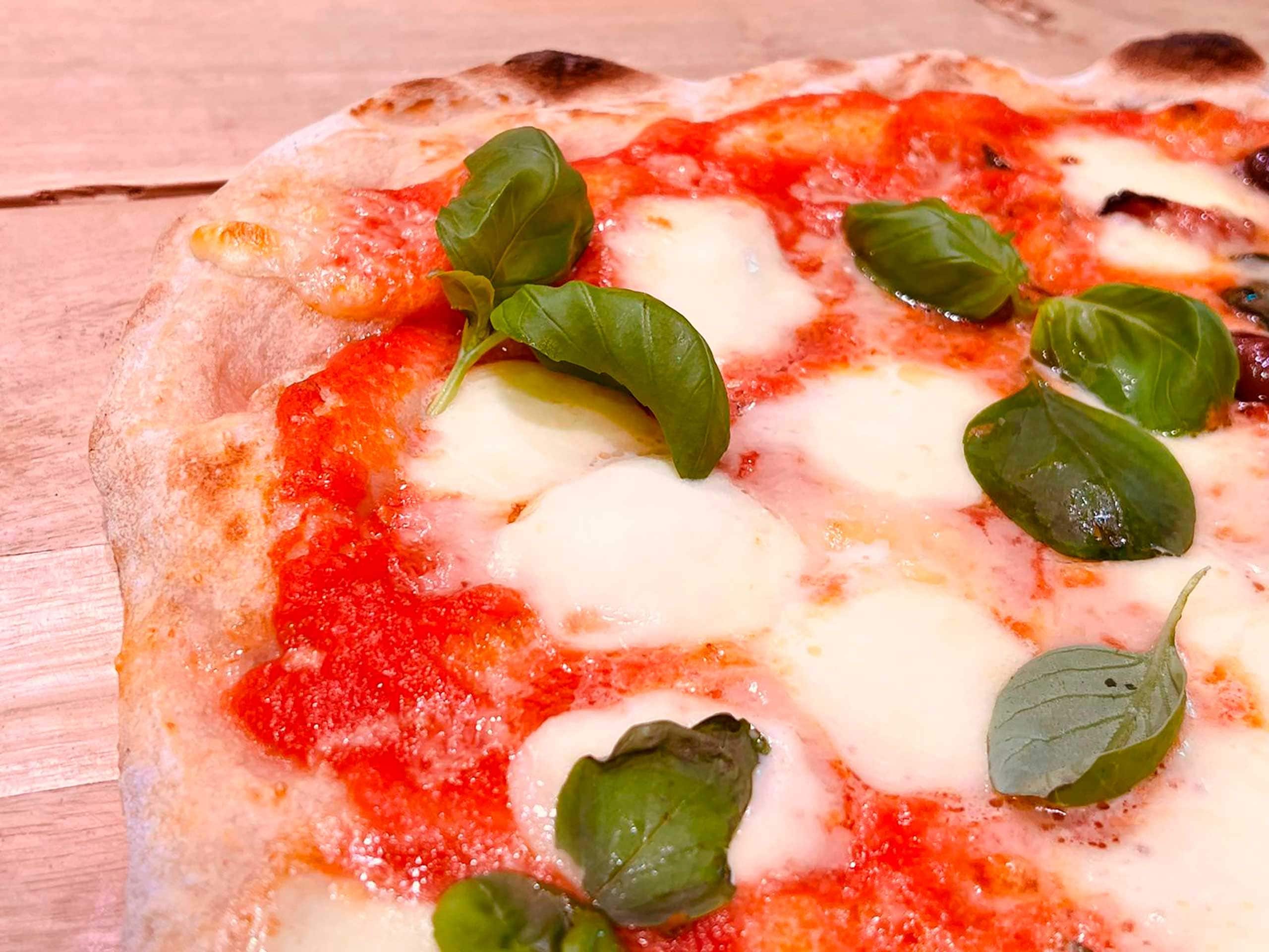 A pizza with cheese and basil leaves on a wooden surface.