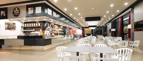 A modern café with a central counter, white chairs, and a tiled floor.