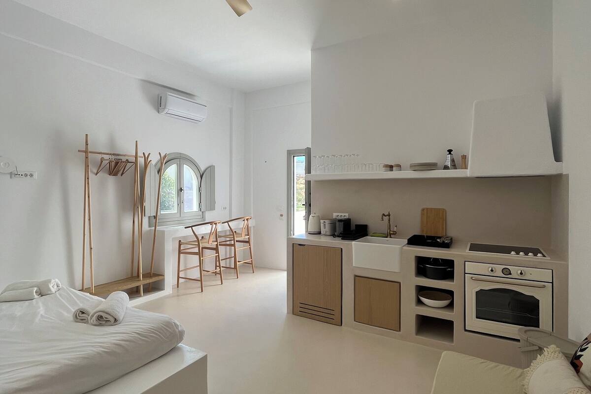 A modern, minimalist bedroom with a large bed, a small round table, and a sofa.