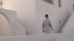 A modern building with a clean, white facade, a central arched window, and a staircase leading to an upper level. - Ios Alcyon Blue Suites (Ios)
