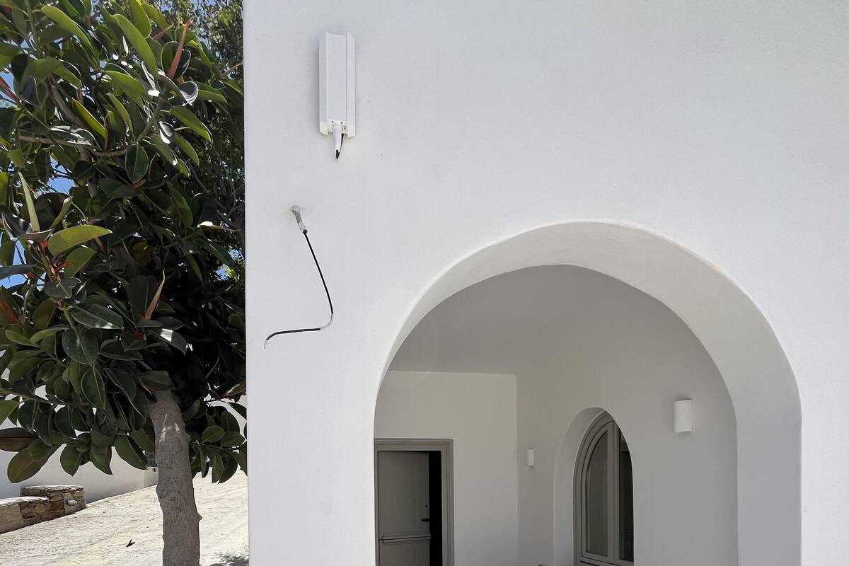 A white building with an arched doorway leading to a room with a table and chairs.