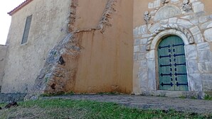 A building with a weathered facade, a large crack, and a stone archway with a green door. - Atypical sunny house - Panoramic terrace at the foot of the Albères (Sorède)