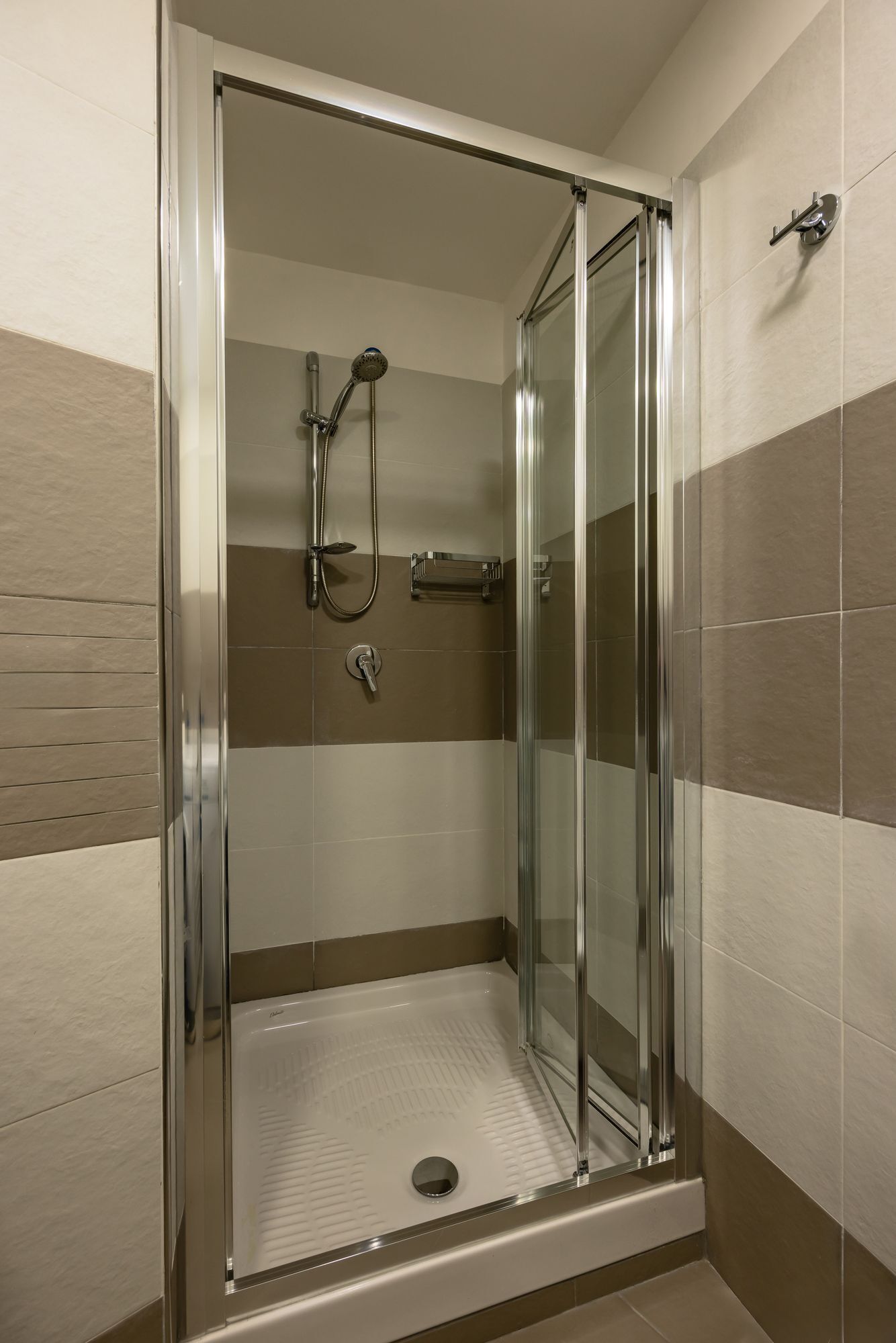 A glass-enclosed shower stall with a handheld showerhead and a wall-mounted faucet.