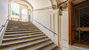 A stone staircase leading to a door with a metal grille, flanked by white walls and arches. - Palazzo Maddaloni Sweet Home By Napoliapartments (Naples)