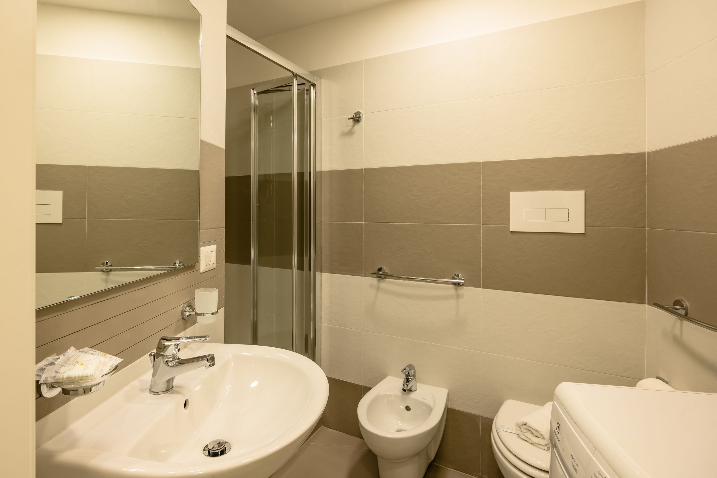 A modern bathroom with a large sink, bidet, toilet, and glass shower enclosure.