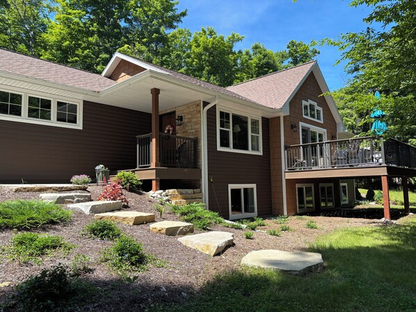A two-story house with a covered porch, stone steps, and a landscaped garden.