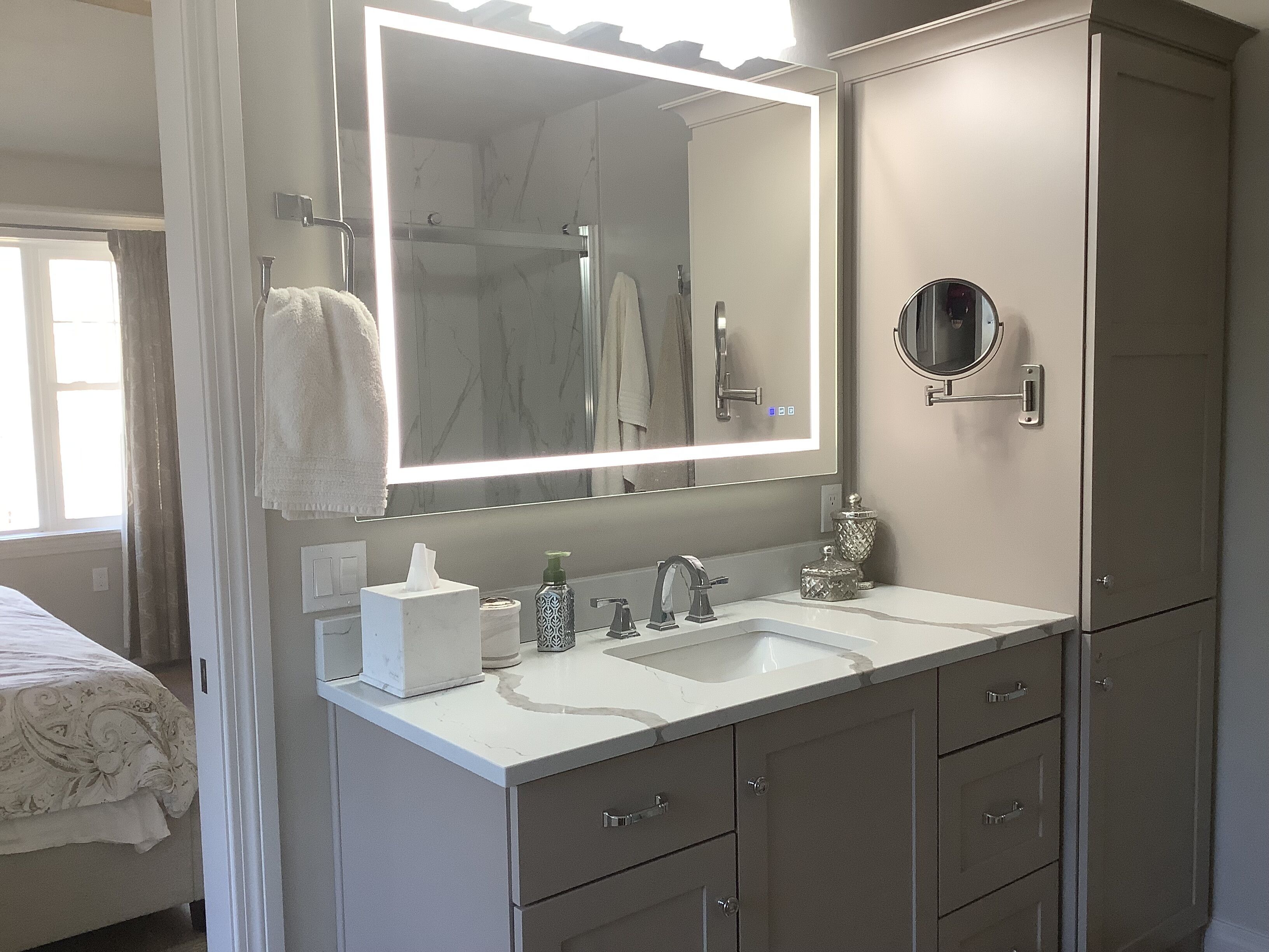 A modern bathroom with a large mirror, two sinks, and a shower.