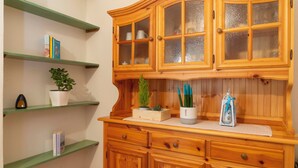 A wooden cabinet with glass doors and a green shelf with books and a potted plant.