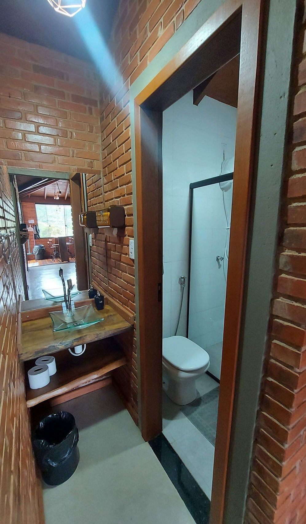 Un baño estrecho con tocador de madera, inodoro y zona de ducha.