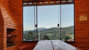 Una mesa de madera con vistas a un paisaje montañoso a través de una ventana con barrotes.