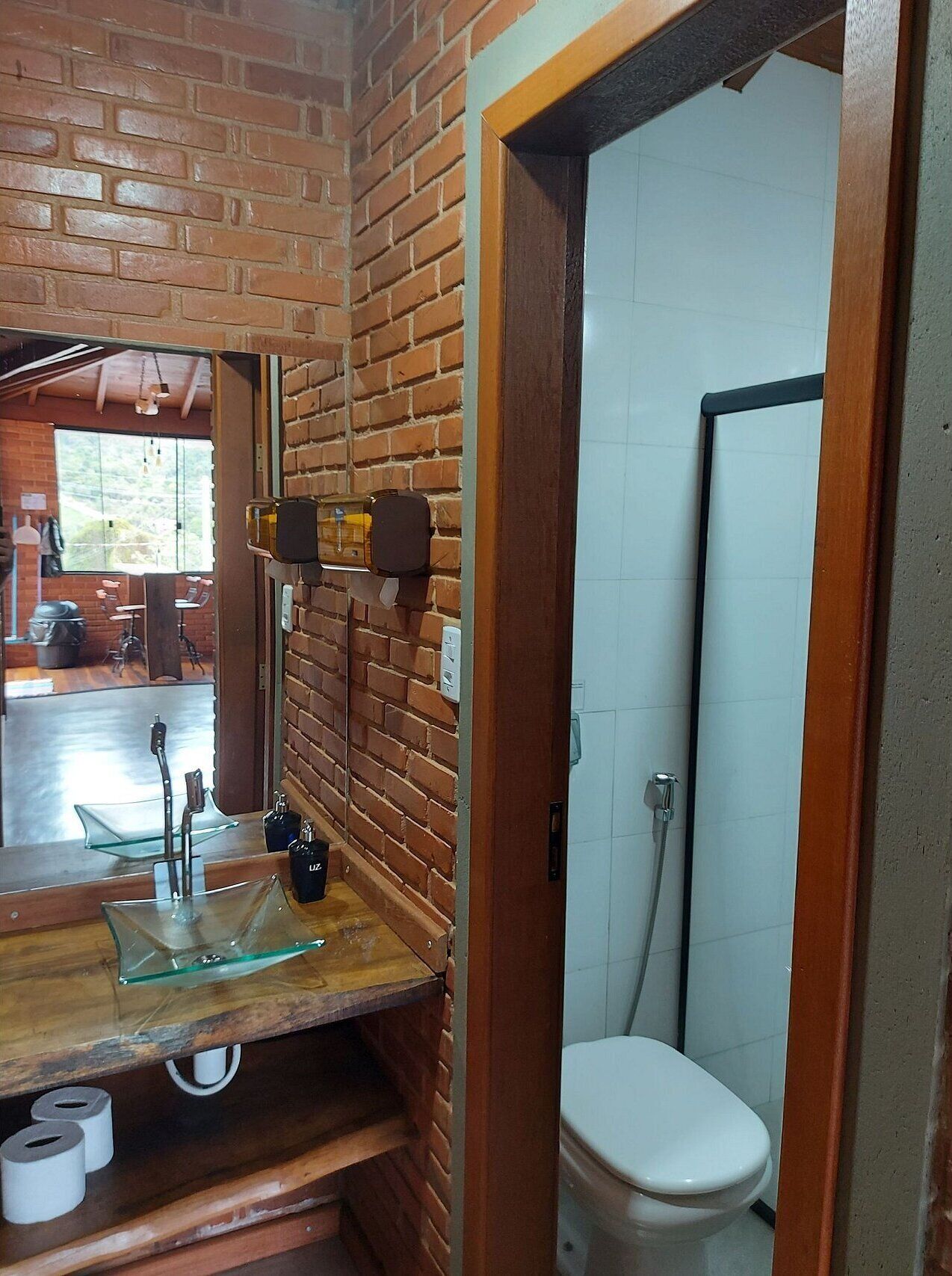 Un baño con tocador de madera, lavabo de vidrio y un inodoro.