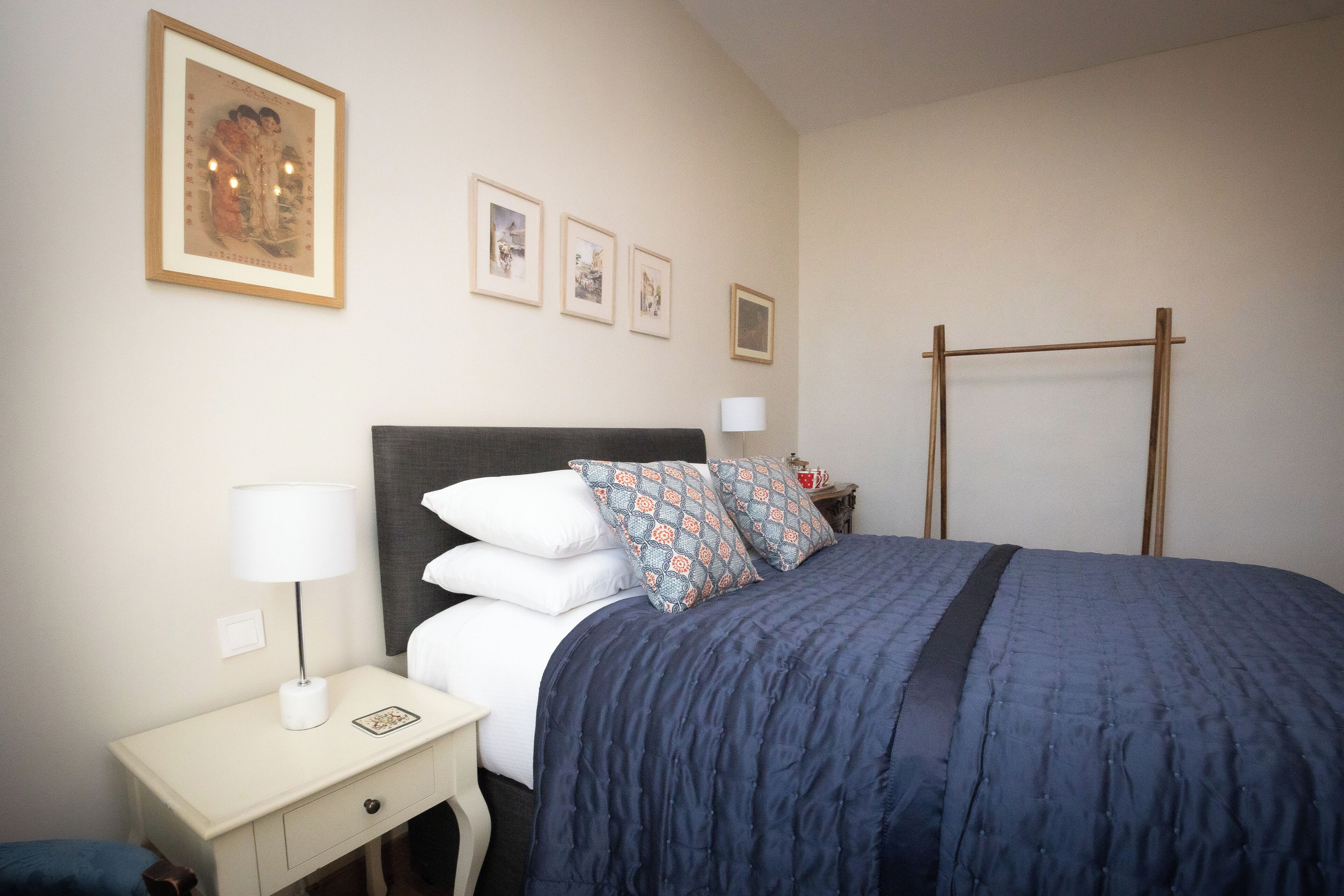 Une chambre à coucher bien rangée, avec un lit, des tables de chevet et des œuvres d’art accrochées au mur.