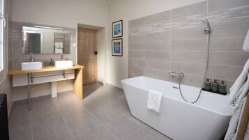 A modern bathroom with a freestanding bathtub, a vanity with a mirror, and two framed pictures on the wall.