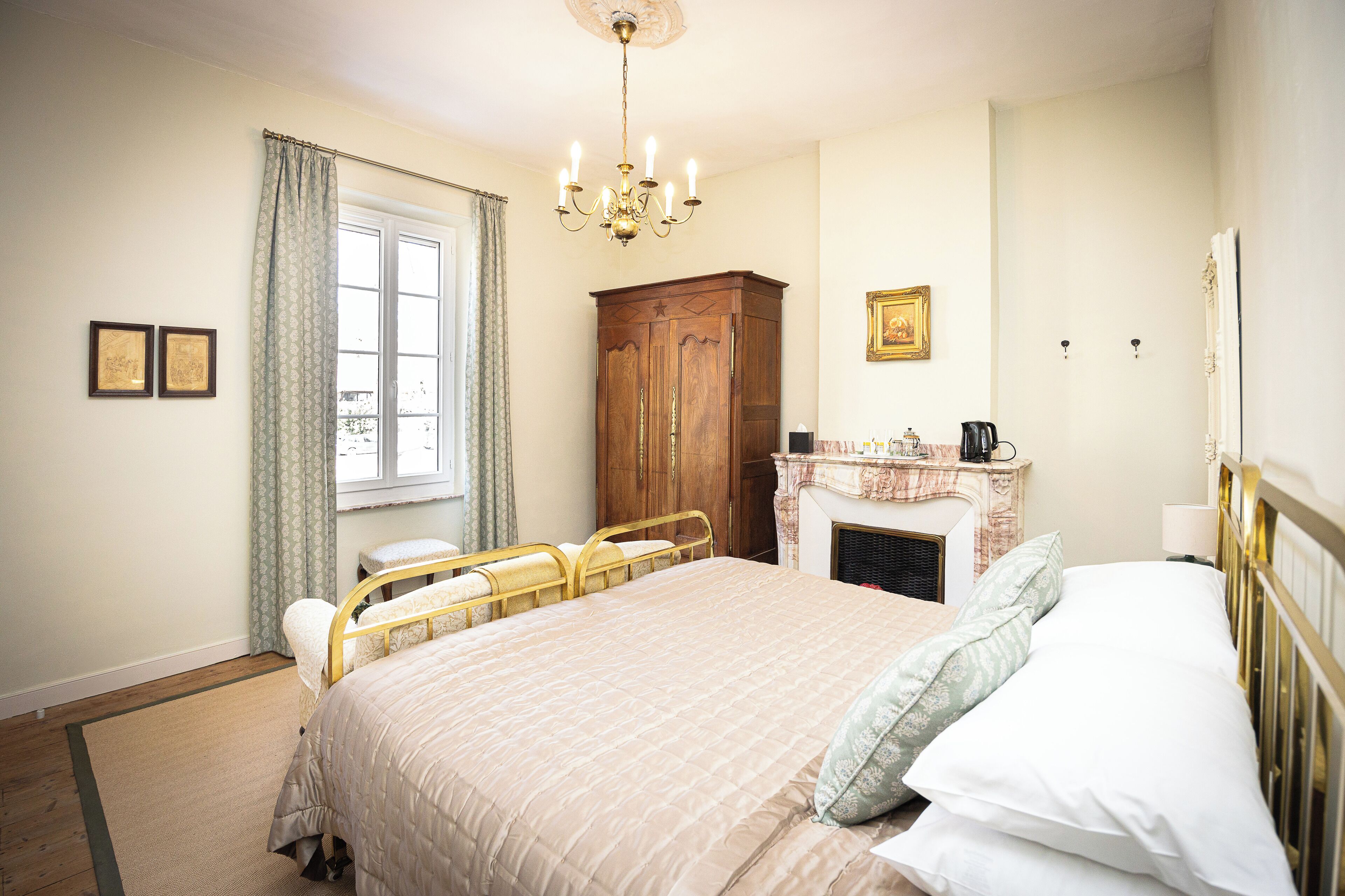 Quarto com cama grande, guarda-roupa de madeira, lareira e lustre.