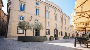Una strada acciottolata con un edificio dotato di ampie finestre e un ingresso centrale.