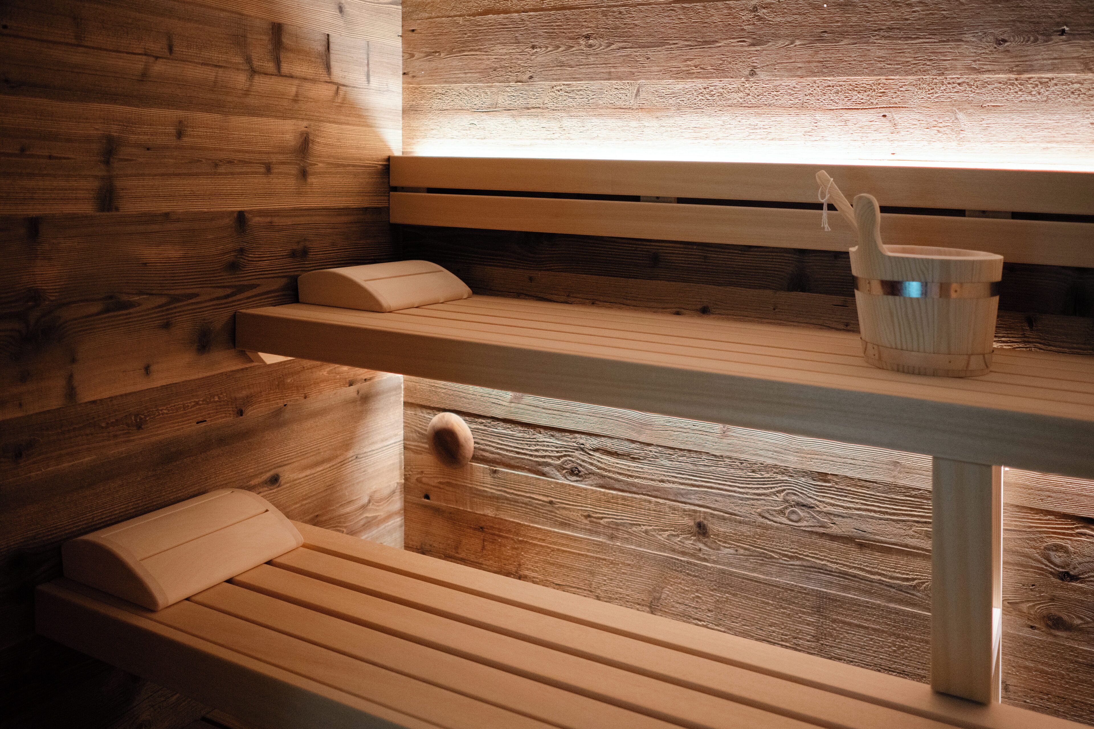 A wooden sauna bench with a wooden bucket and a ladle.