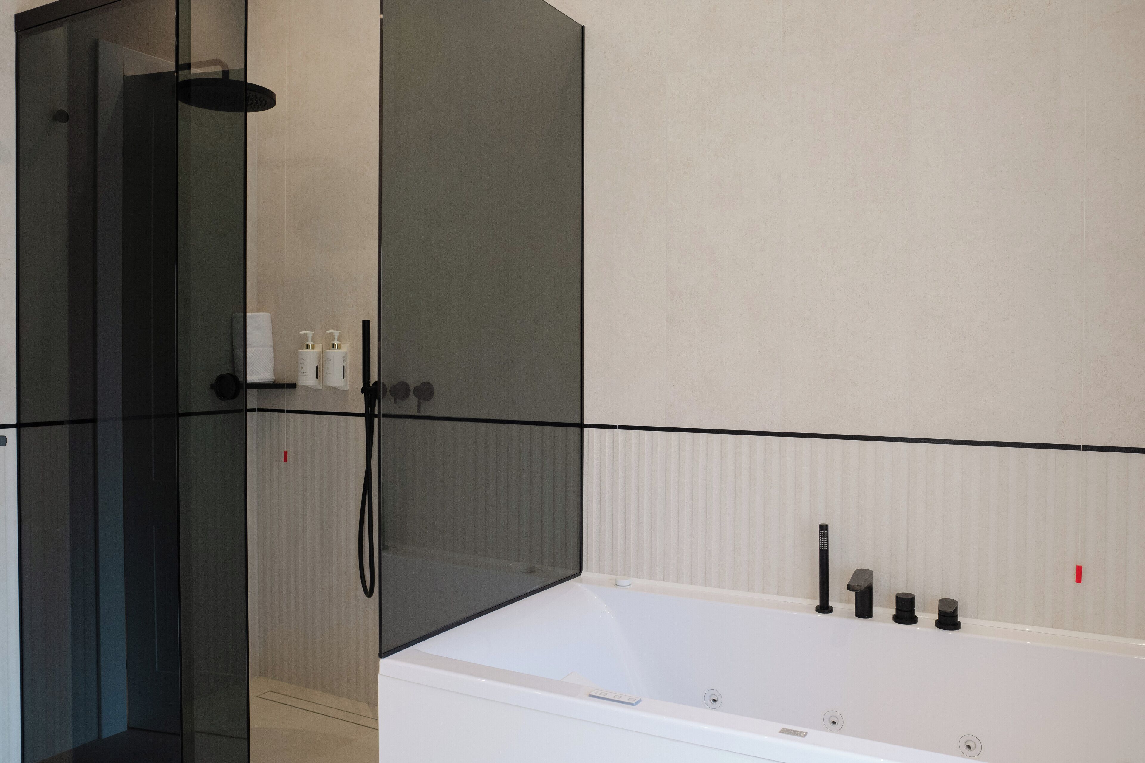 A modern bathroom with a glass-enclosed shower, a white bathtub, and a towel rack.