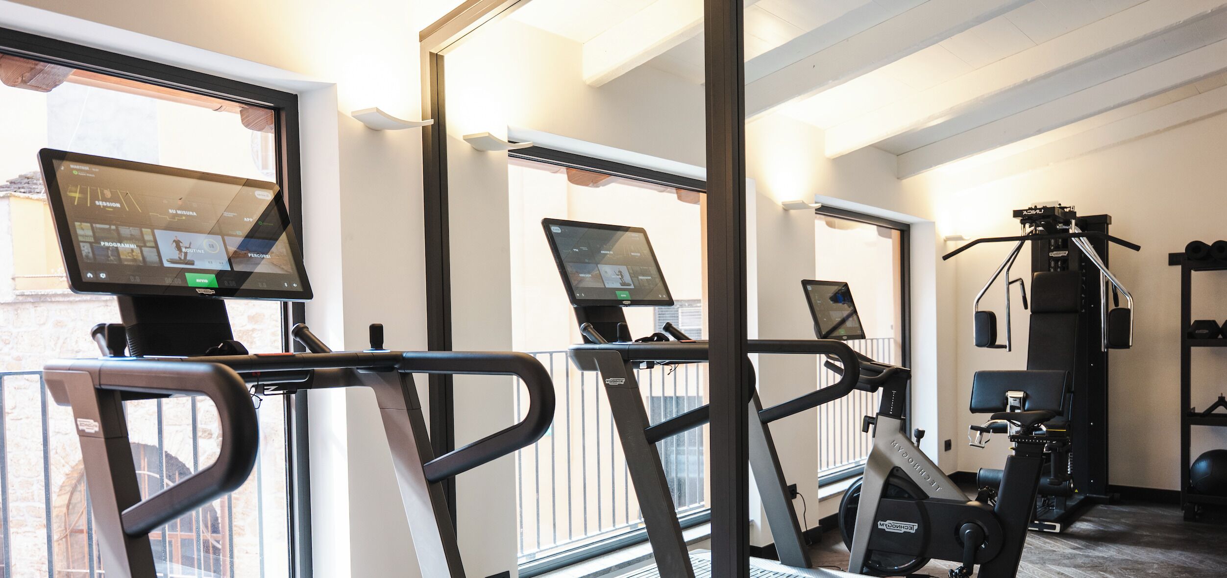Un gimnasio con cintas de correr, bicicletas estáticas y máquinas de pesas.