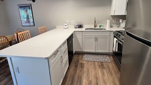 Een moderne keuken met witte kasten, een roestvrijstalen koelkast en een eethoek met houten meubels.