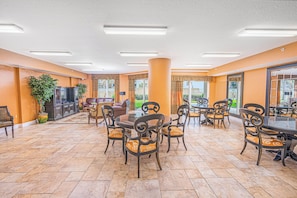 Un espace intérieur spacieux comprenant une table à manger entourée de chaises, un canapé et un téléviseur.