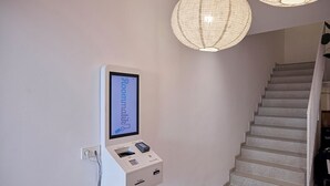 Una postazione digitale per il check-in con uno schermo che mostra “Roommates” e una scala.