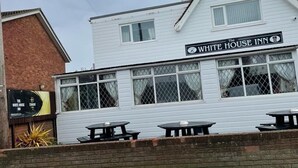 Le White House Inn, reconnaissable à sa façade blanche, ses nombreuses fenêtres et ses tables à l’extérieur.