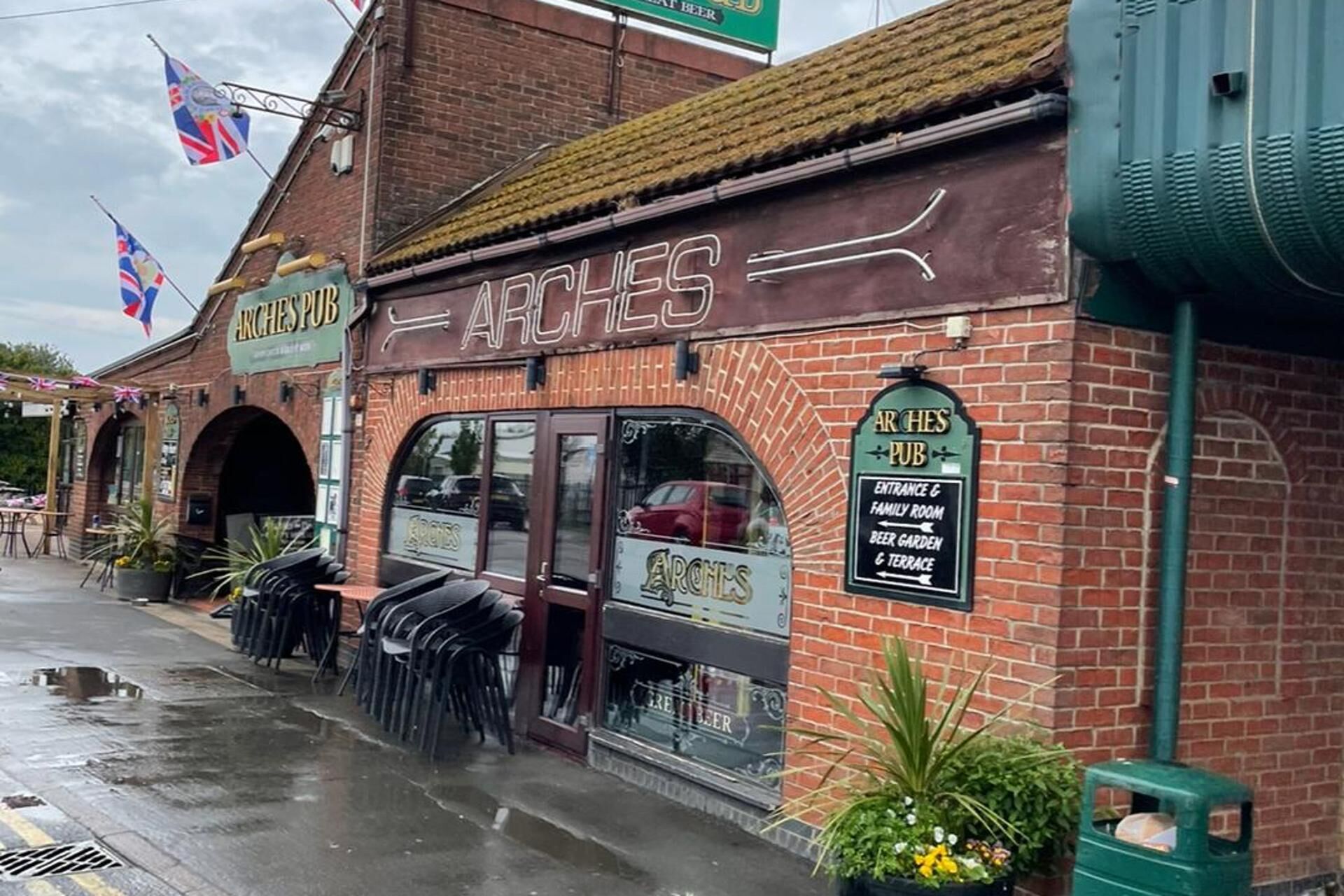 A brick building with a sign reading "ARCHES PUB" and a smaller sign indicating "ENTRANCE & FAMILY ROOM, BEER GARDEN & TERRACE".
