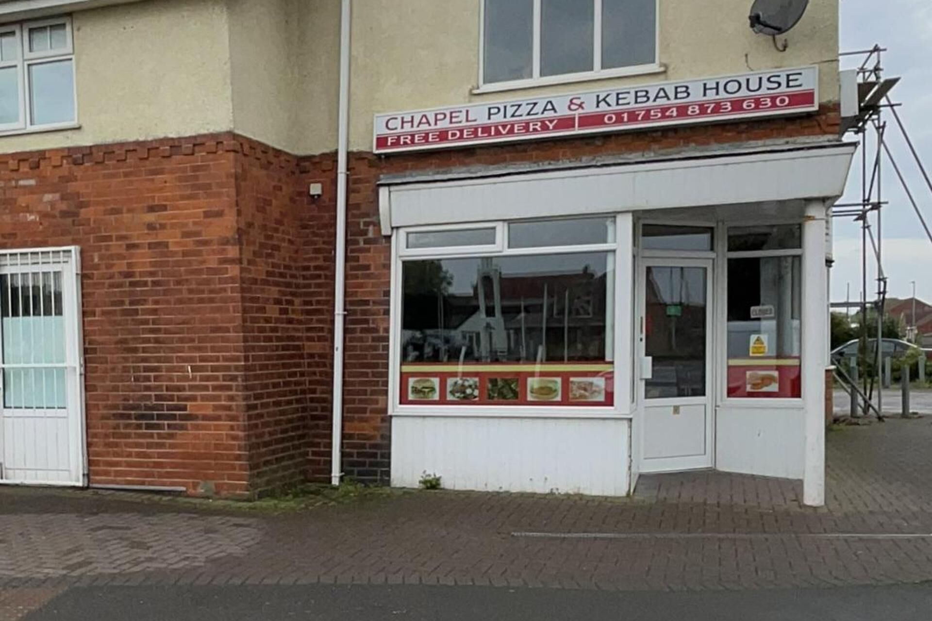 A brick building with a sign for 'Chapel Pizza & Kebab House' offering free delivery.