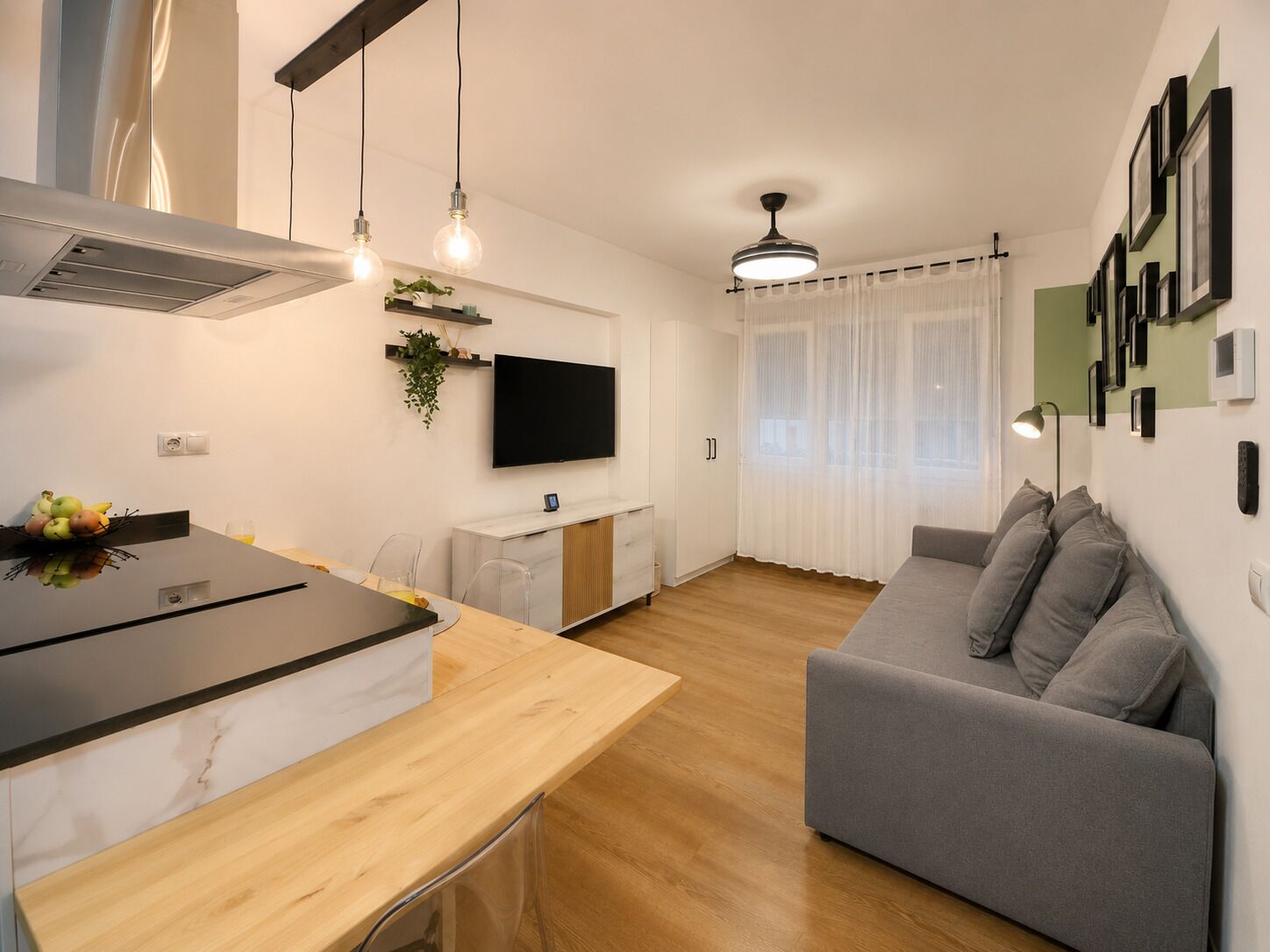 Een moderne woonruimte met een keuken, eethoek en een grijze bank.