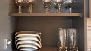 A kitchen with a Bosch microwave, shelves with glassware, plates, and a pitcher.