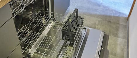 Cocina compacta con lavavajillas, encimera de madera y pileta de acero inoxidable.