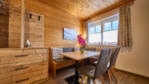 A wooden interior with a dining table, chairs, a bench, and a cabinet.