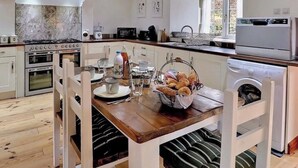 Une cuisine moderne avec une table à manger en bois, des meubles blancs et un pare-feu en pierre.