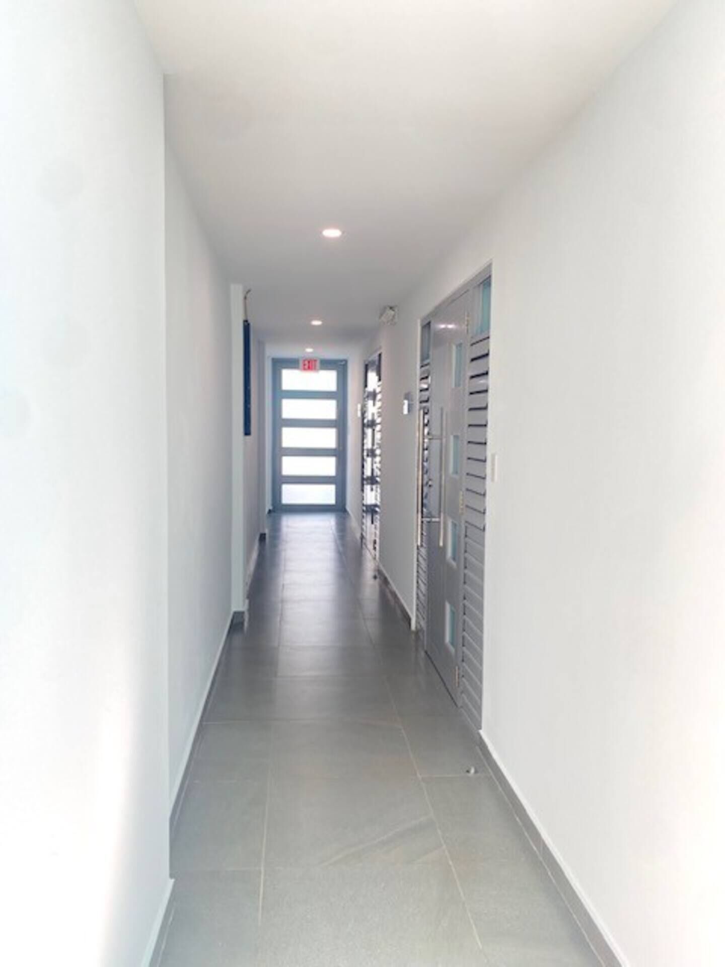 A long, narrow hallway with a tiled floor and white walls.