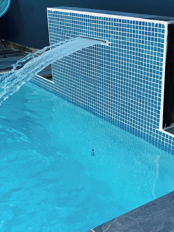 Relax by the pool, surrounded by a tranquil water feature and an atmosphere.