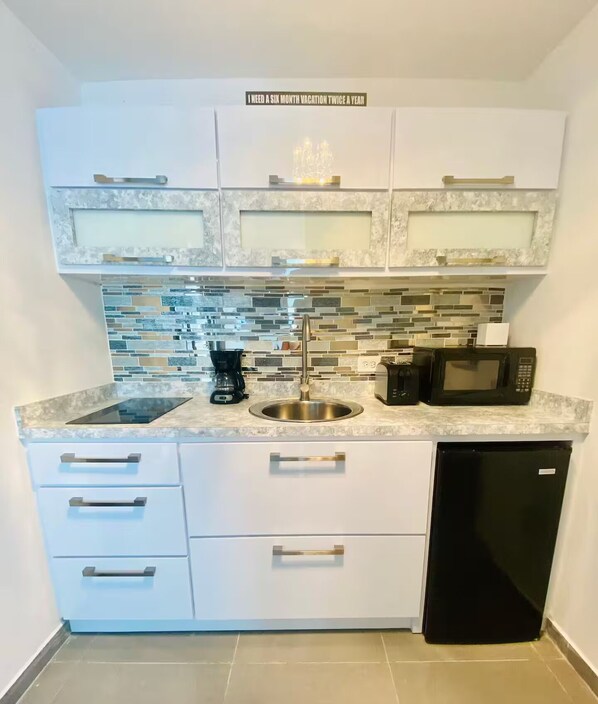 A compact kitchen with a stainless steel sink, a coffee maker, a microwave, and a dishwasher.