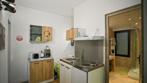 Een kleine keuken met een spoelbak, magnetron en kastjes.