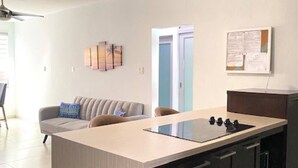 A modern kitchen with a central island, dark cabinetry, and a light-colored countertop.