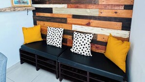 A room with a wooden wall panel design, a bench with yellow cushions, and a framed picture on the wall.