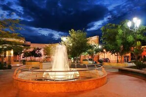 Stunning courtyard fountain surrounded by lush greenery and warm-toned buildings.