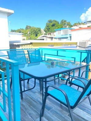 Enjoy a tranquil outdoor space with a glass table and comfortable seating, surrounded by lush greenery and city views.