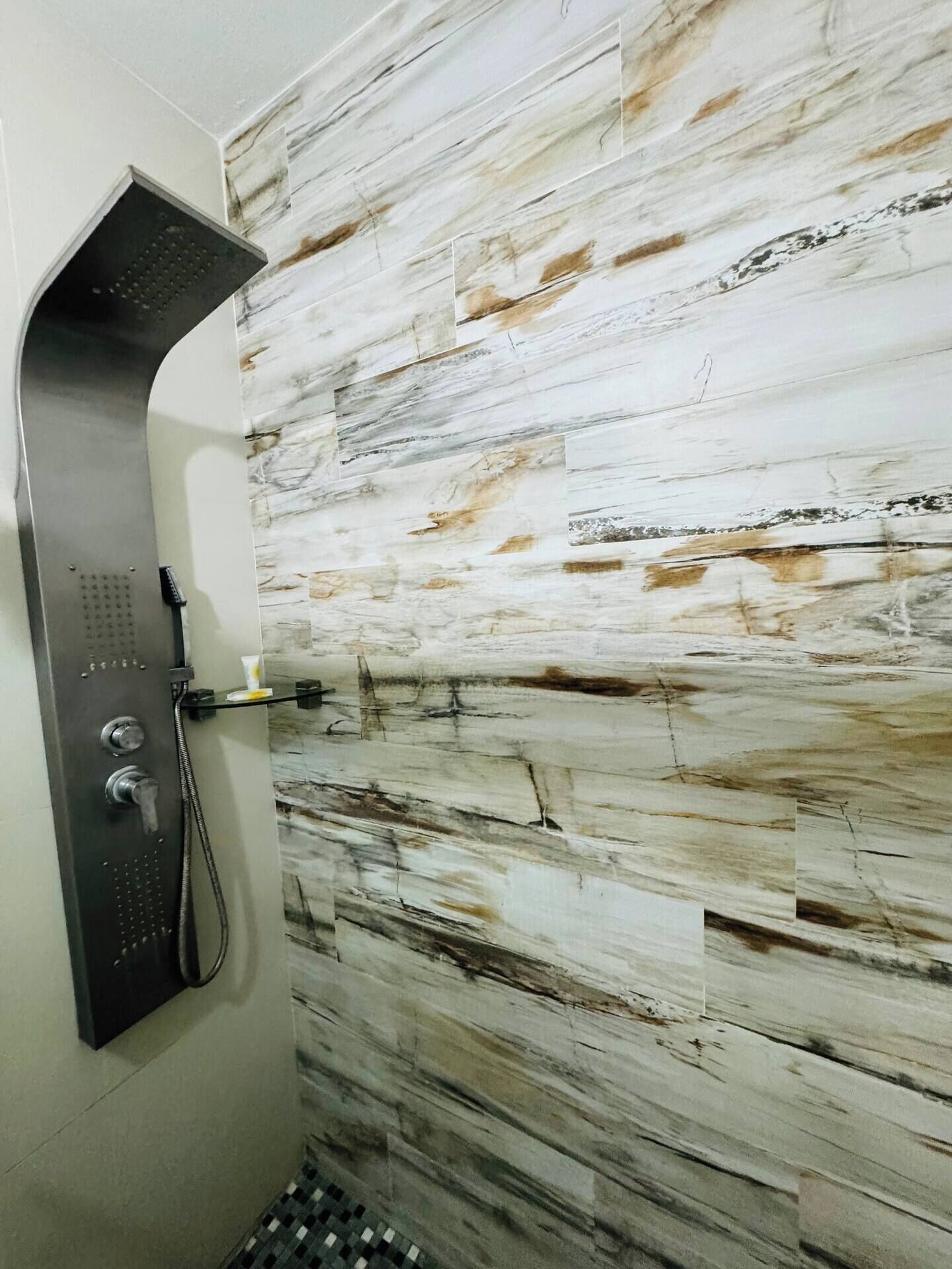 Una ducha con pared curva y un diseño de azulejos que imita el mármol.