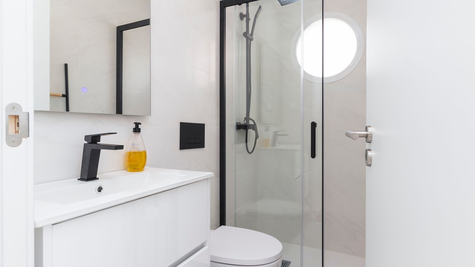 A modern bathroom with a glass shower enclosure, a white sink, a mirror, and a toilet.