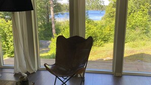 Una stanza con vista su un lago, una sedia pieghevole, un tavolo di legno e una lampada.