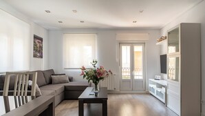 Een moderne woonkamer met een bank, een salontafel met een vaas, en een televisie op een kast.